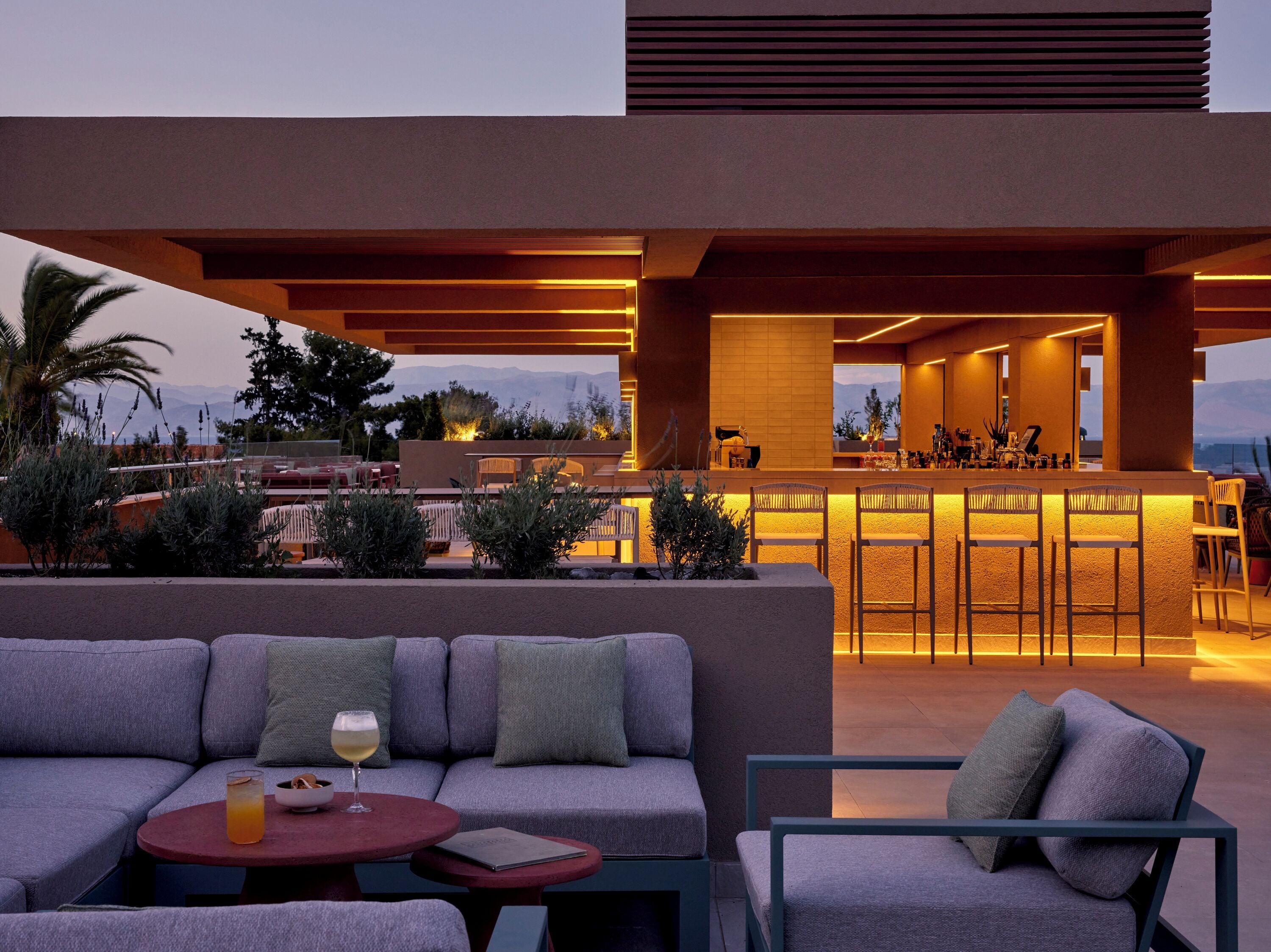 An outdoor seating area with a bar, cushioned seating, and a view of the mountains.