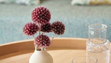 A wooden tray with a vase of purple flowers, two glasses of water, and a card on a wooden surface.