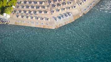 Een privéstrand, ligstoelen aan het strand, parasols, strandlakens