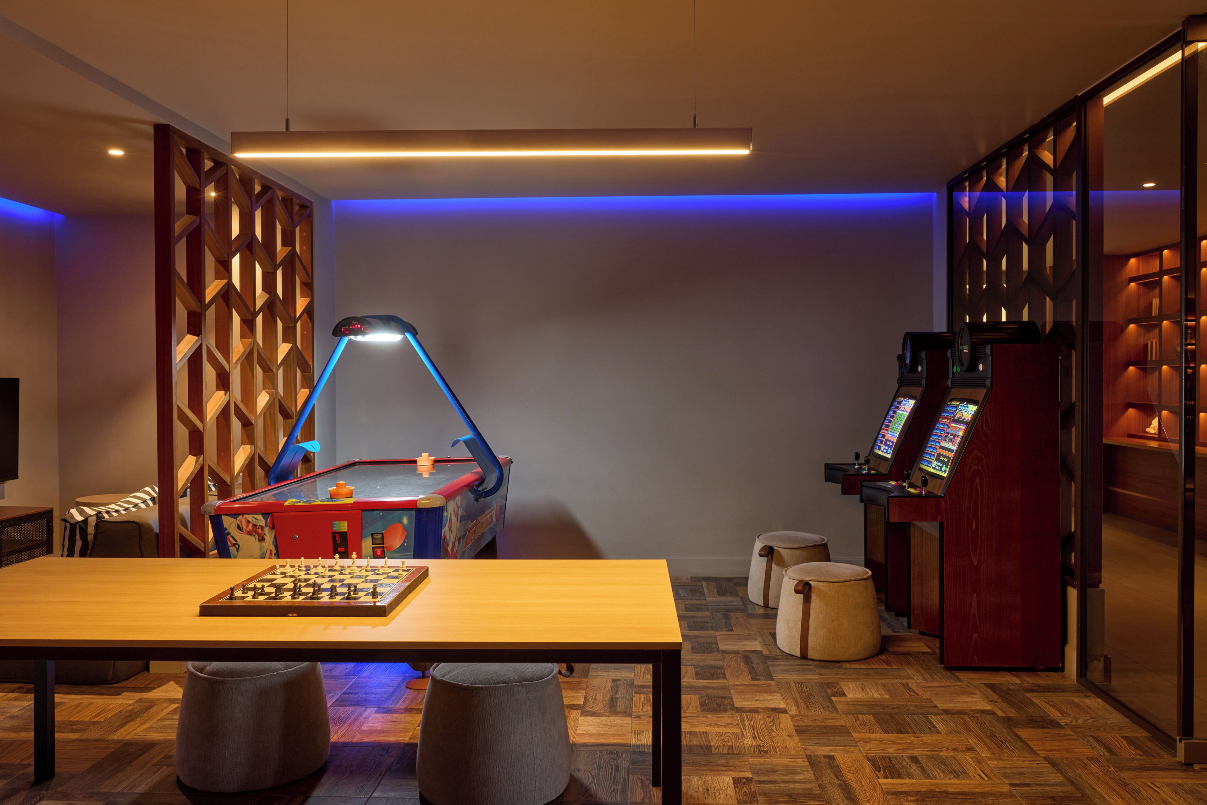 Una habitación con una mesa de ajedrez, una mesa de billar y una zona de videojuegos.