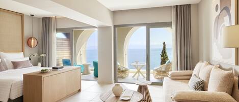 Una habitación de hotel moderna con cama, escritorio, sofá y balcón con vista al mar.