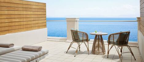 A balcony with two wicker chairs, a small round table, and a sofa with towels.