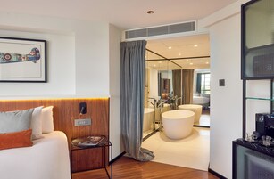 Una camera d'albergo moderna con un letto, un comodino e un'ampia finestra.