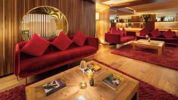 A modern living room with a red sofa, matching cushions, and a round mirror.