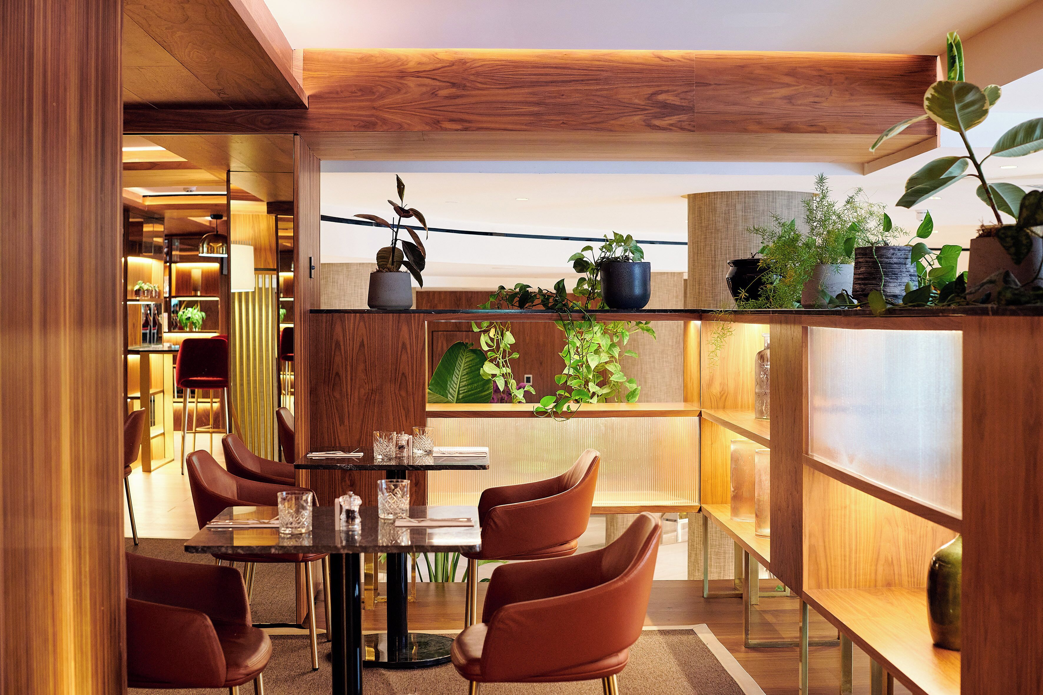Un espace repas moderne avec une table ronde, quatre chaises marron et un plafond en bois.