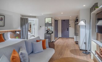 Habitación de hotel moderna con una cama grande, un escritorio, un baño y vistas al pasillo.