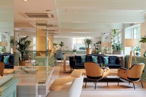 A spacious lobby with a modern seating area, a glass partition, and a view of the adjacent room.