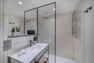 Ein modernes Badezimmer mit Waschbecken, Spiegel und Duschbereich.