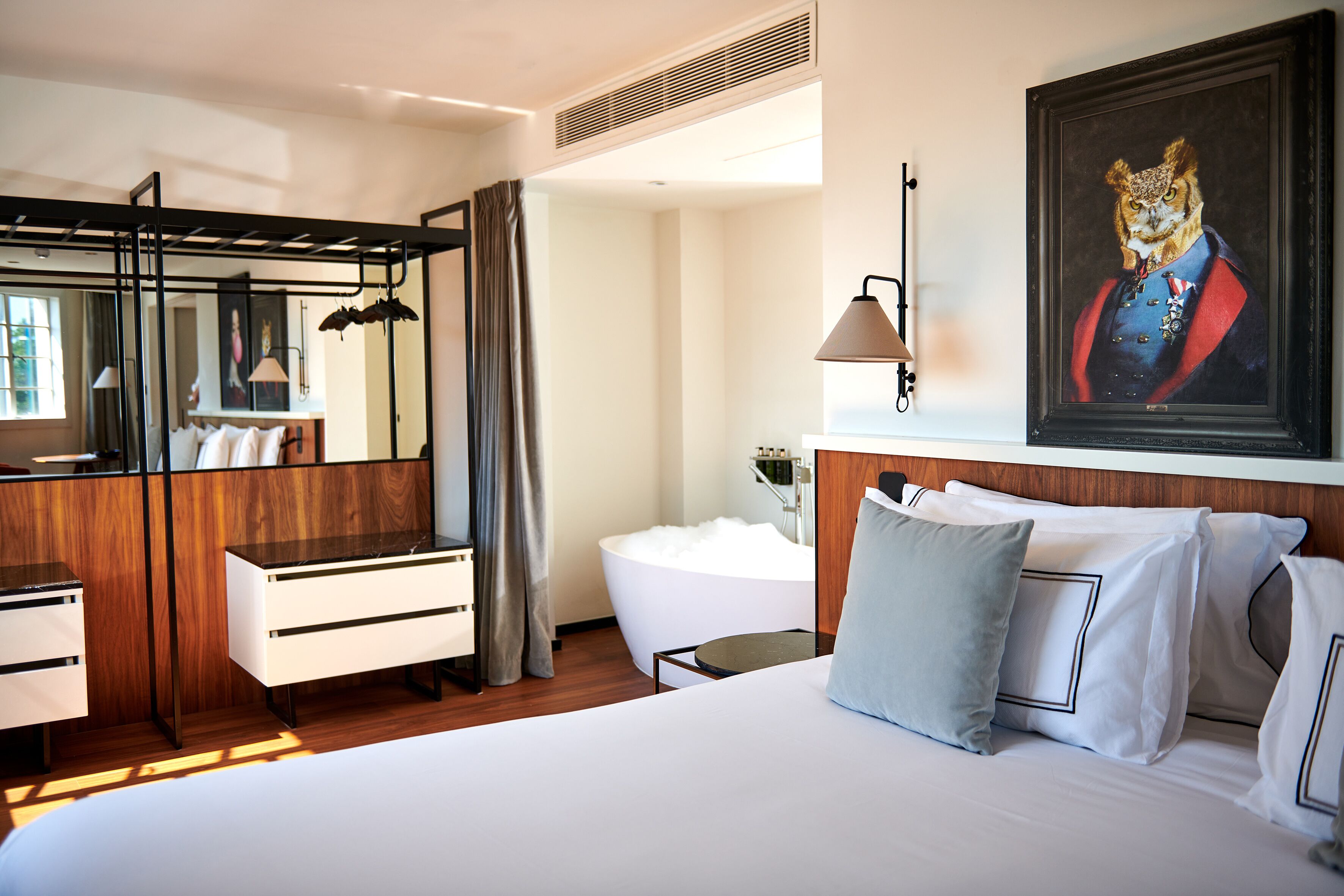 Una habitación de hotel con cama, escritorio, silla, bañera y un espejo grande.
