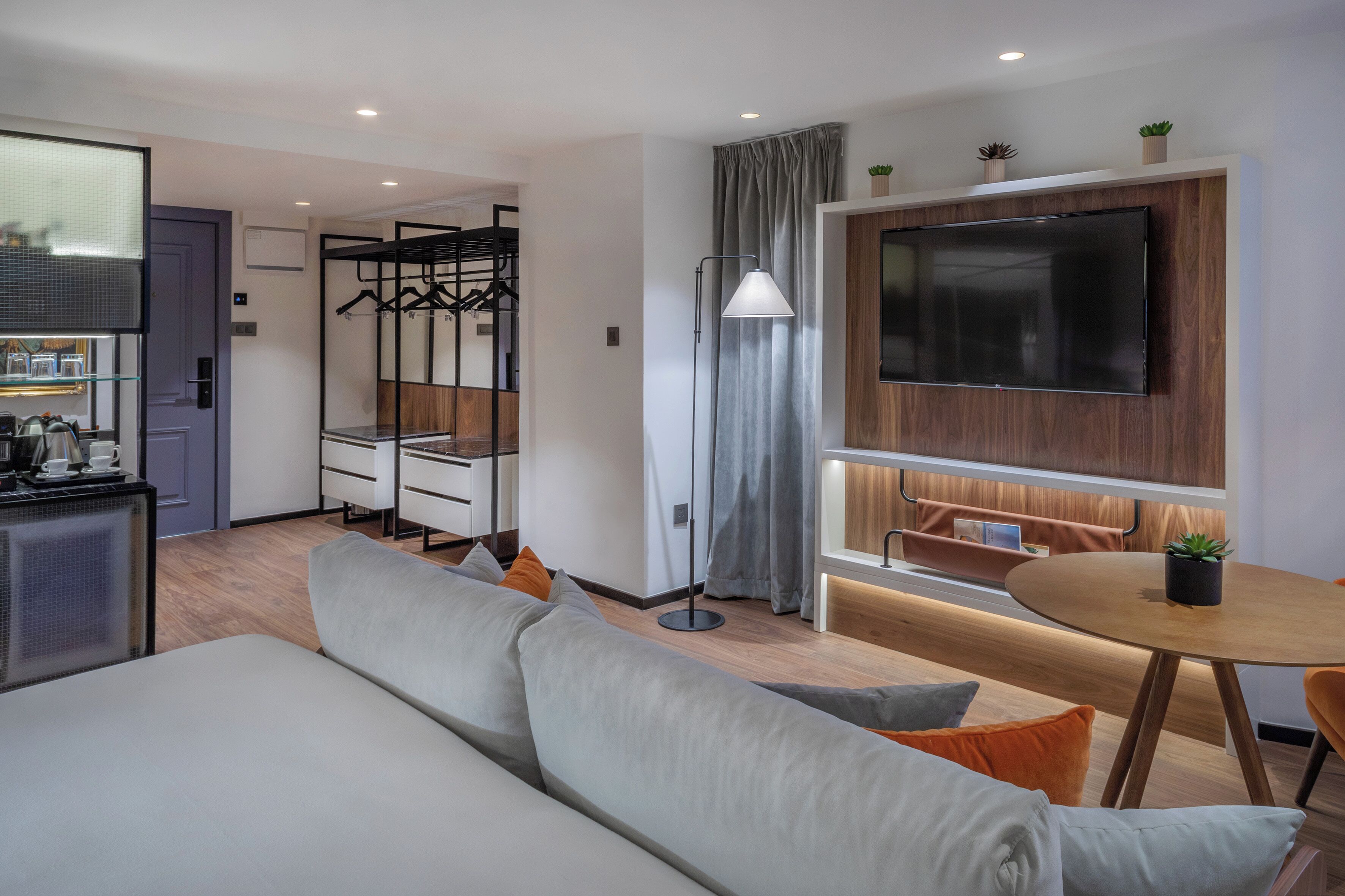 Una habitación de hotel moderna con sofá, mesa de comedor, televisor y kitchenette.
