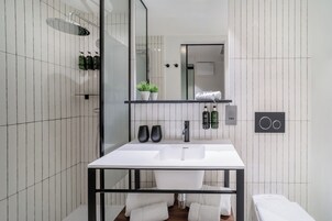 Un bagno moderno con un lavandino bianco, accessori neri e cabina doccia in vetro.