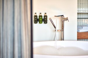 A bathroom with a bathtub, a shower, and three bottles of shampoo on the wall.