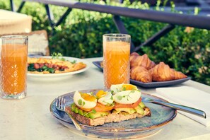Ein Frühstückstisch mit Croissants, einem Teller Eier und Orangensaftgläsern.