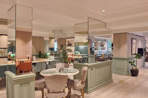 A spacious dining area with a high ceiling, large mirrors, and a central island with seating.