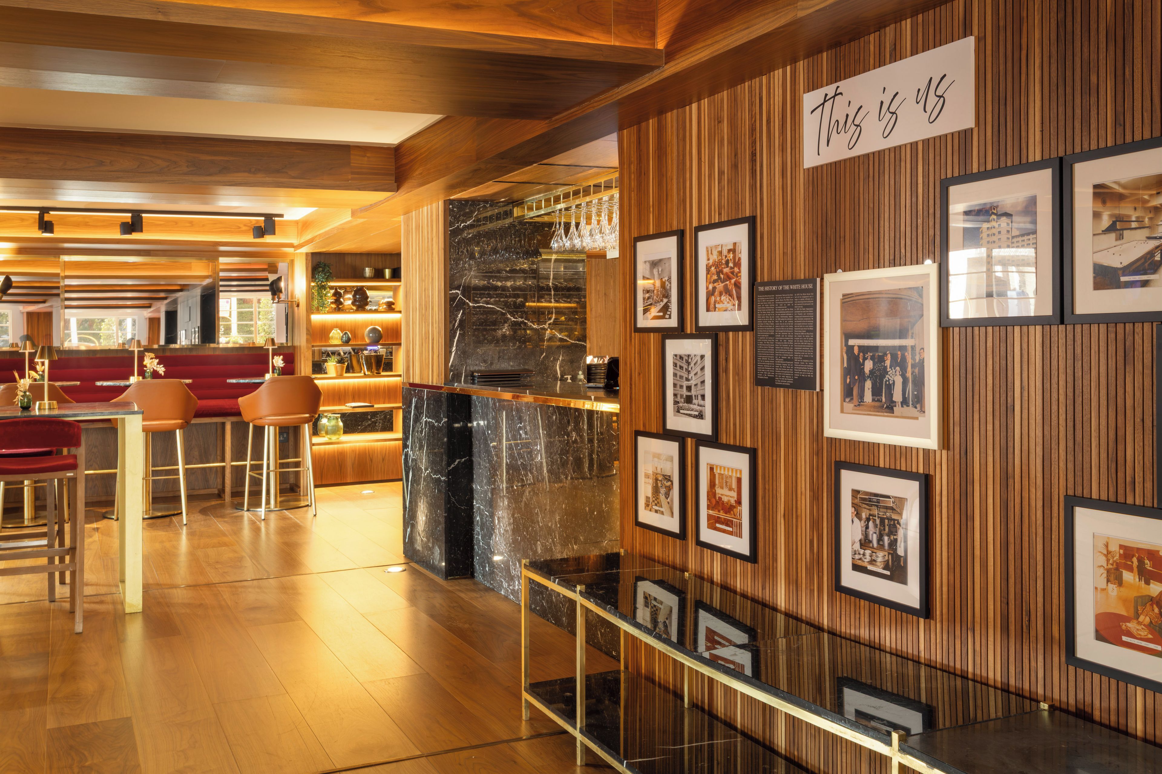 A modern interior with a bar area, wooden paneling, and framed historical photos on the wall.