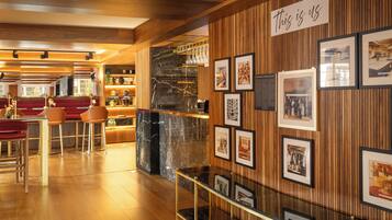 A modern interior with a bar area, wooden paneling, and framed historical photos on the wall.