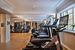 Un gimnasio con varias cintas de correr, bicicletas estáticas y máquinas de pesas.