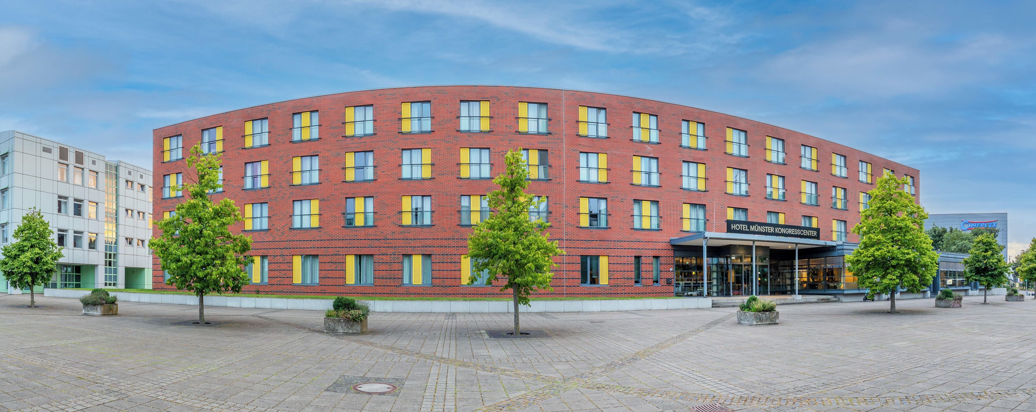 A red-brick hotel with a curved facade, multiple windows, and a covered entrance.