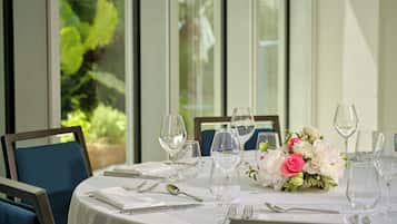 A dining table set for six with white tablecloth, clear glassware, and a floral centerpiece.