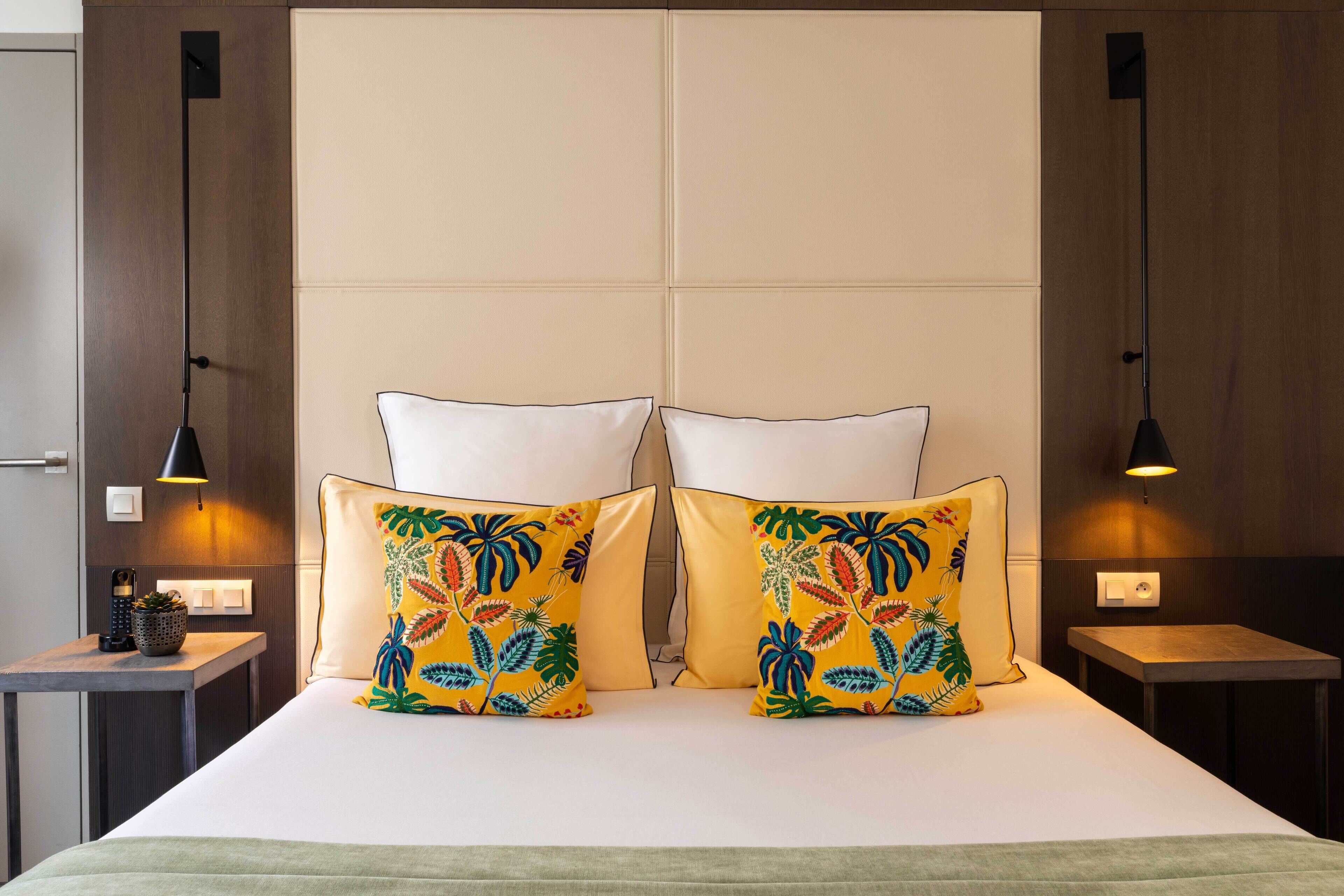 Una habitación de hotel con una cama grande, dos mesitas de noche y dos lámparas de pared.