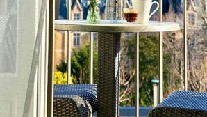 A balcony with a table set with a vase of flowers, a bottle, and a cup. - Villa Saxe Eiffel (Paris)