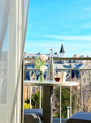 A balcony with a table set with a vase of flowers, a bottle, and a cup. - Villa Saxe Eiffel (Paris)