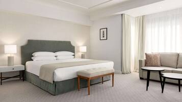 Ein Hotelzimmer mit einem großen Bett, Nachttischen, einer Bank, einem Sofa und einem kleinen Tisch.
