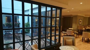 A hotel lobby with a large glass wall, multiple seating areas, and a view of the outdoor patio. - Hotel Avenue Louise Brussels - Trademark Collection by Wyndham (Brussels)