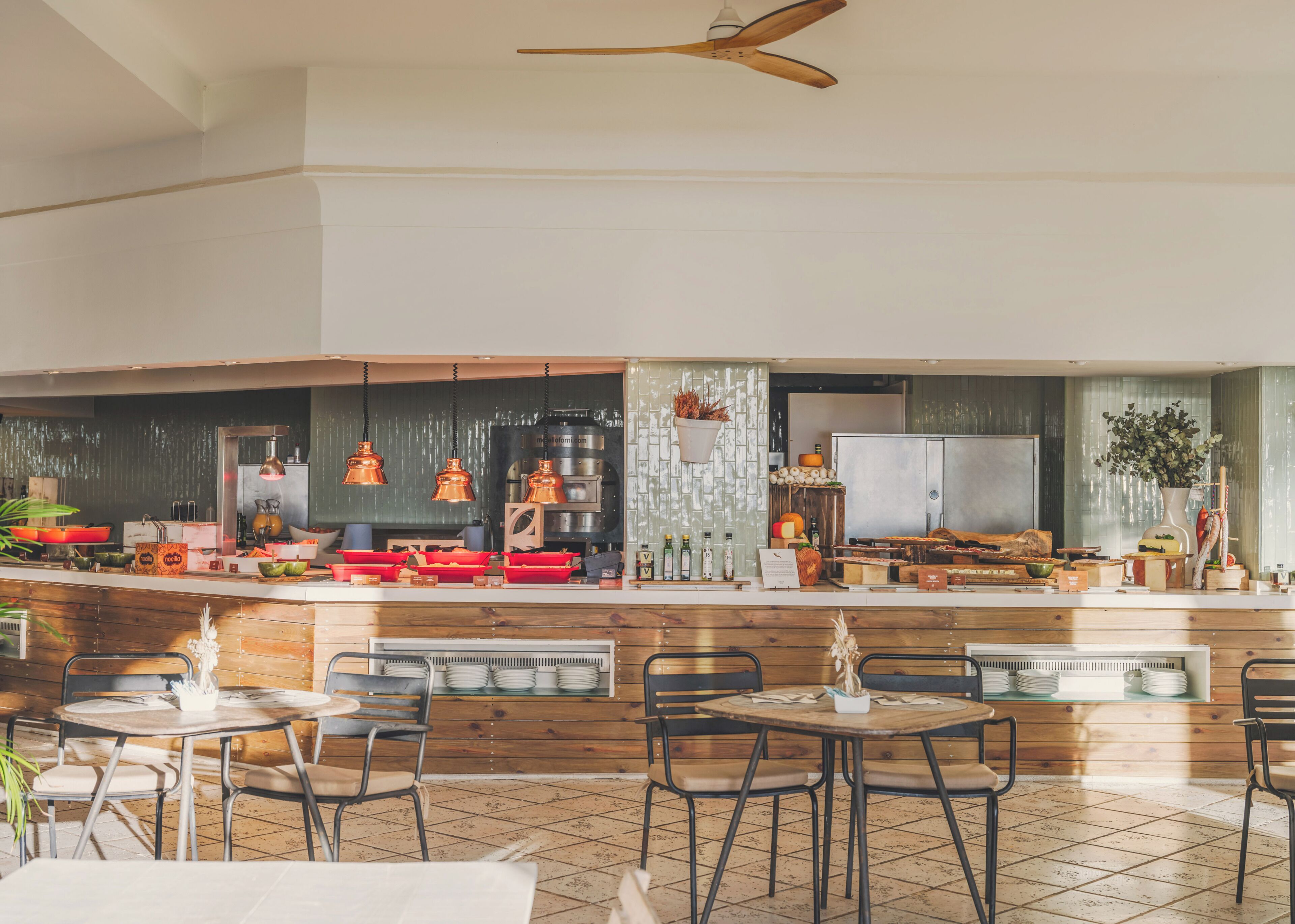 A modern kitchen with a bar area, wooden furniture, and hanging pendant lights.