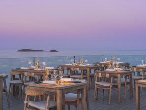 A dining area with tables and chairs, overlooking a body of water. - Meliá Ibiza  - Adults Only (Santa Eulalia del Rio)