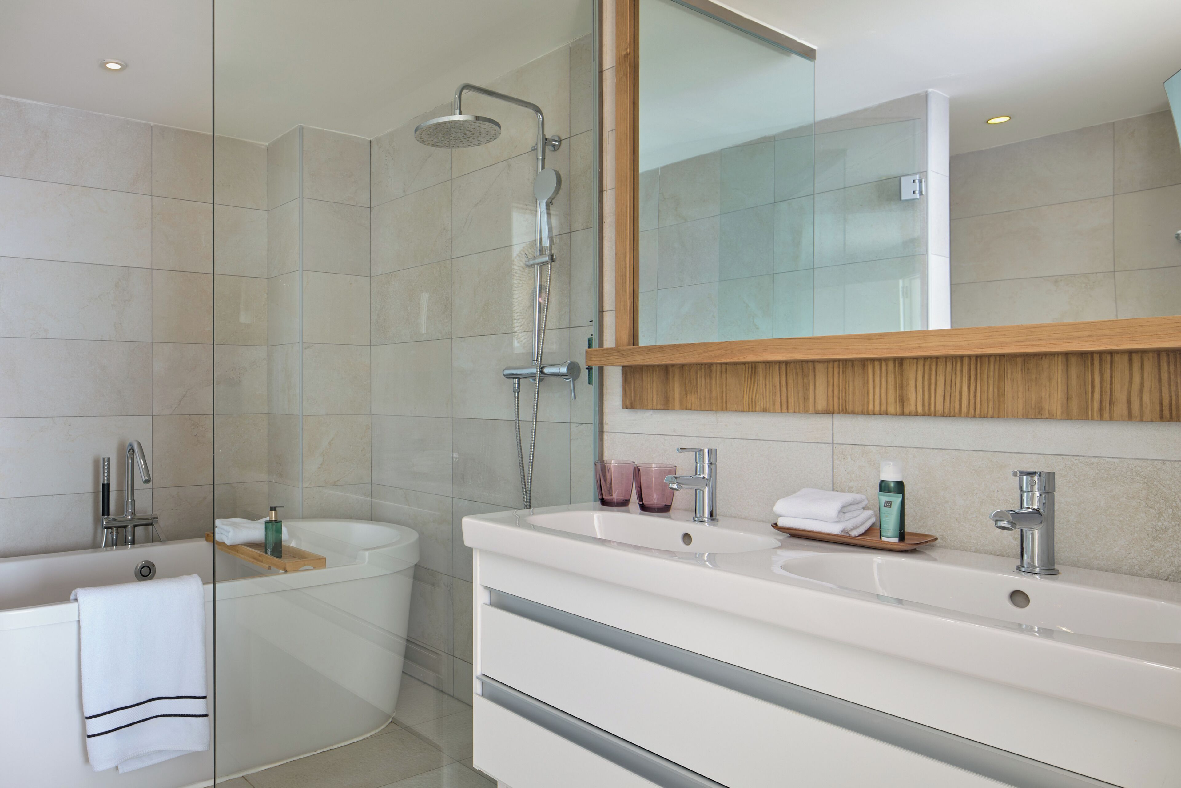A modern bathroom with a bathtub, a shower, and a vanity with a mirror.