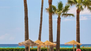 A pool area with palm trees, lounge chairs, and umbrellas. - Sol Milanos Pingüinos (Alayor)