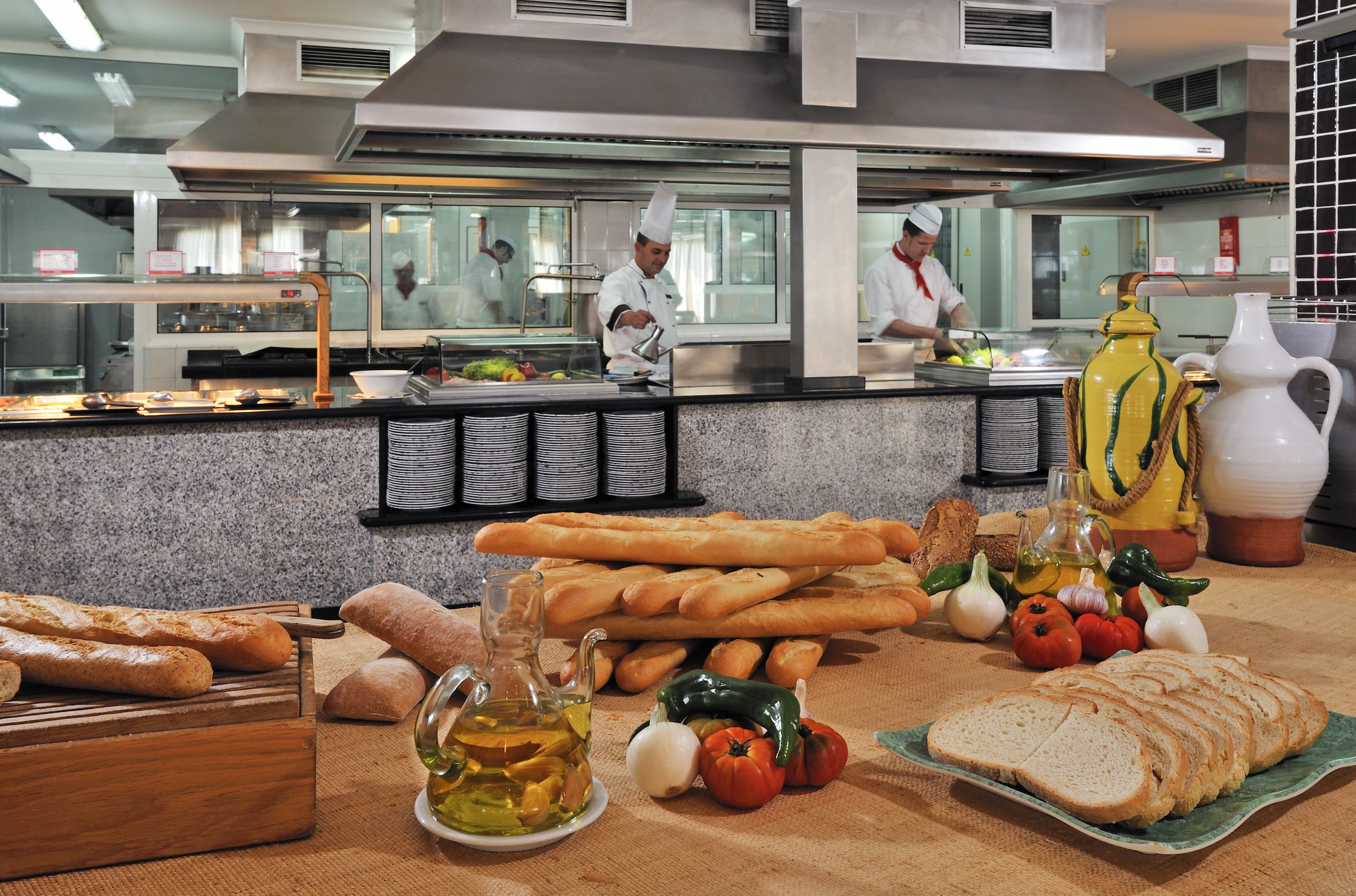 A buffet setup with various breads, vegetables, and a chef preparing food.