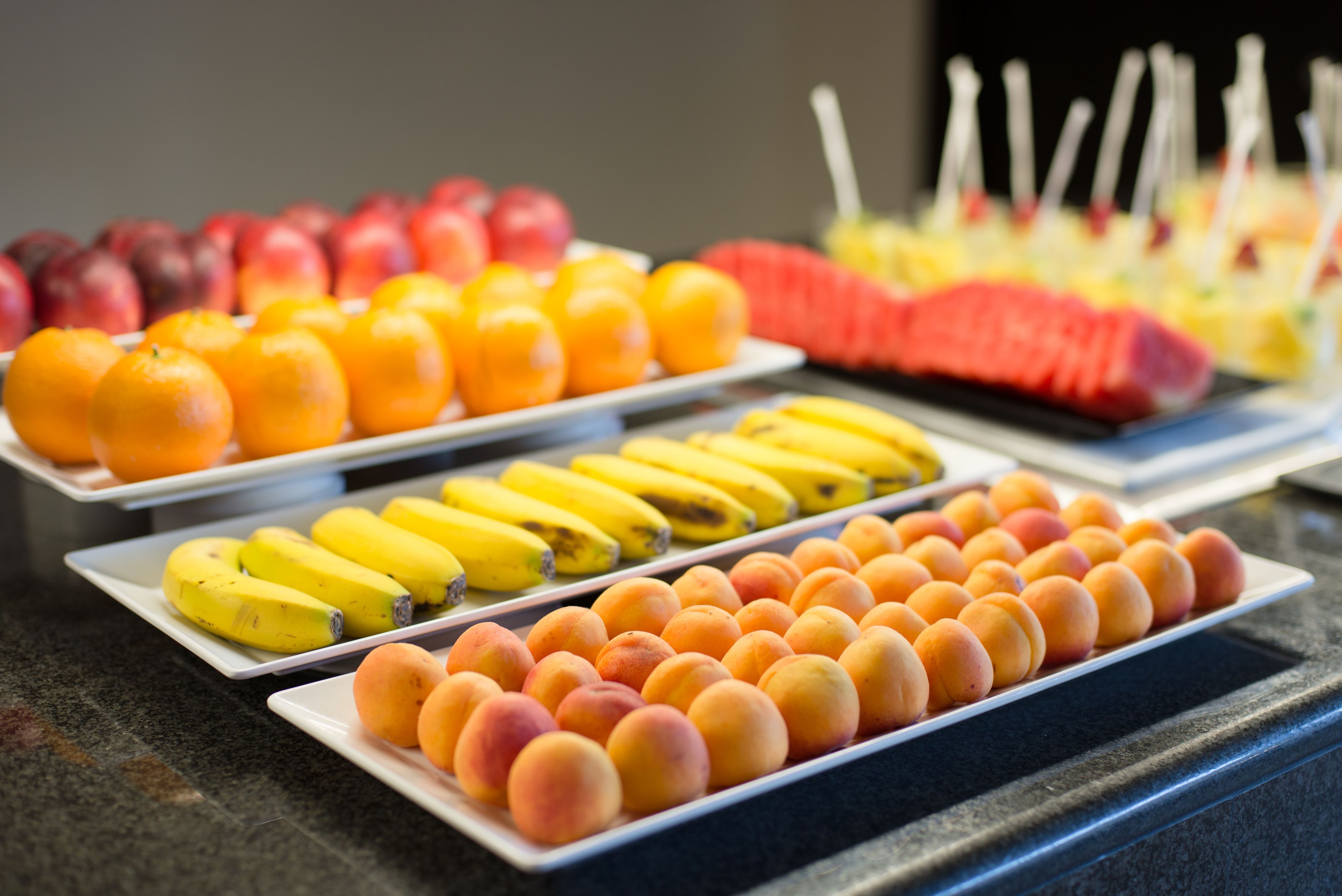 Un buffet proposant une variété de fruits, notamment des oranges, des bananes et des pêches.