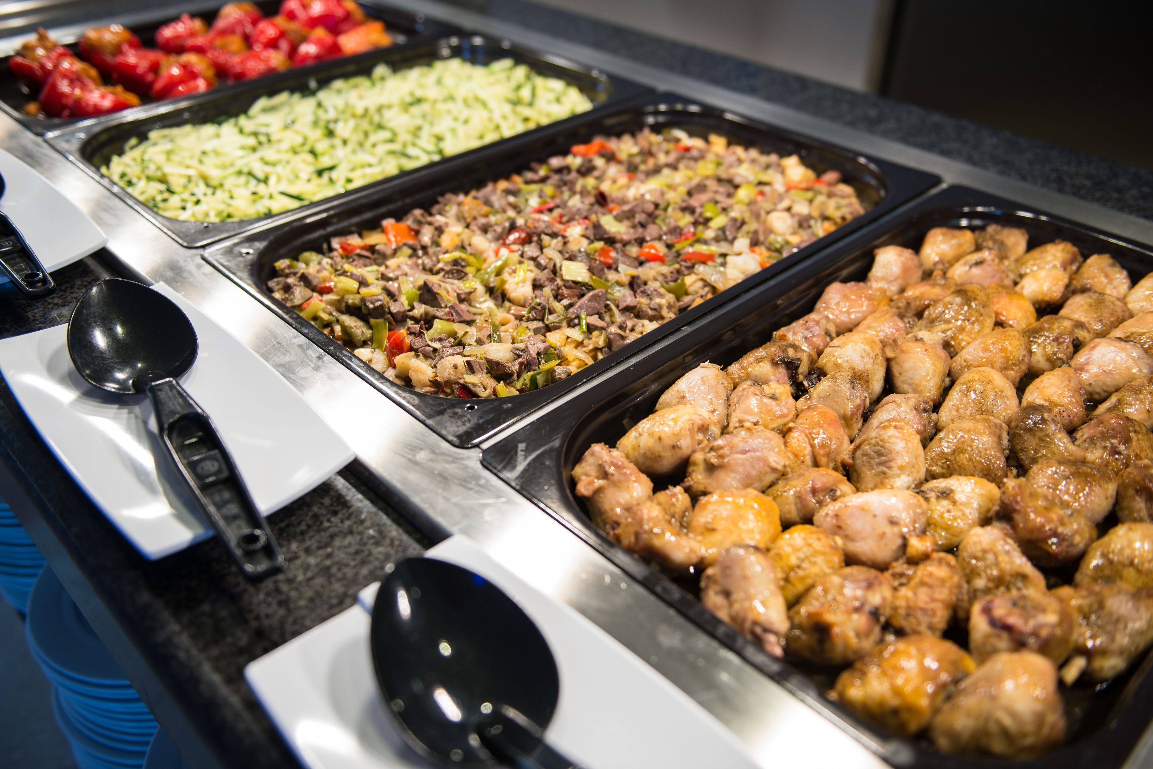 Een buffet met diverse gerechten, waaronder vlees, groenten en salades.