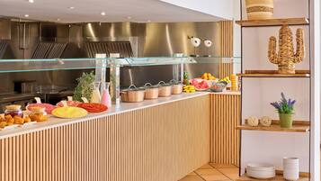Un espace buffet proposant une variété de plats, une vitrine réfrigérée et des plantes décoratives.