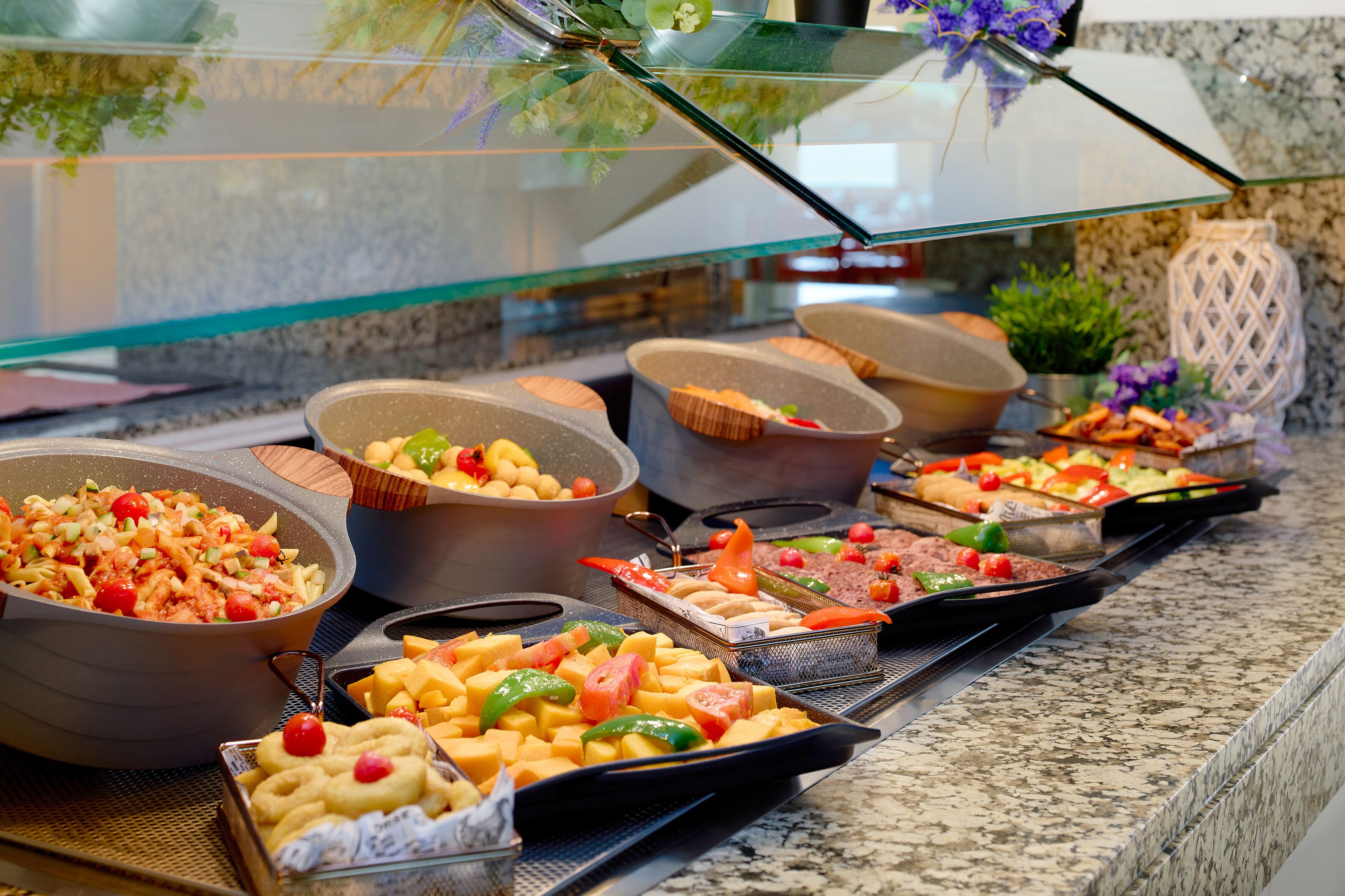 En buffet med forskellige retter, herunder salater, frugt og desserter.