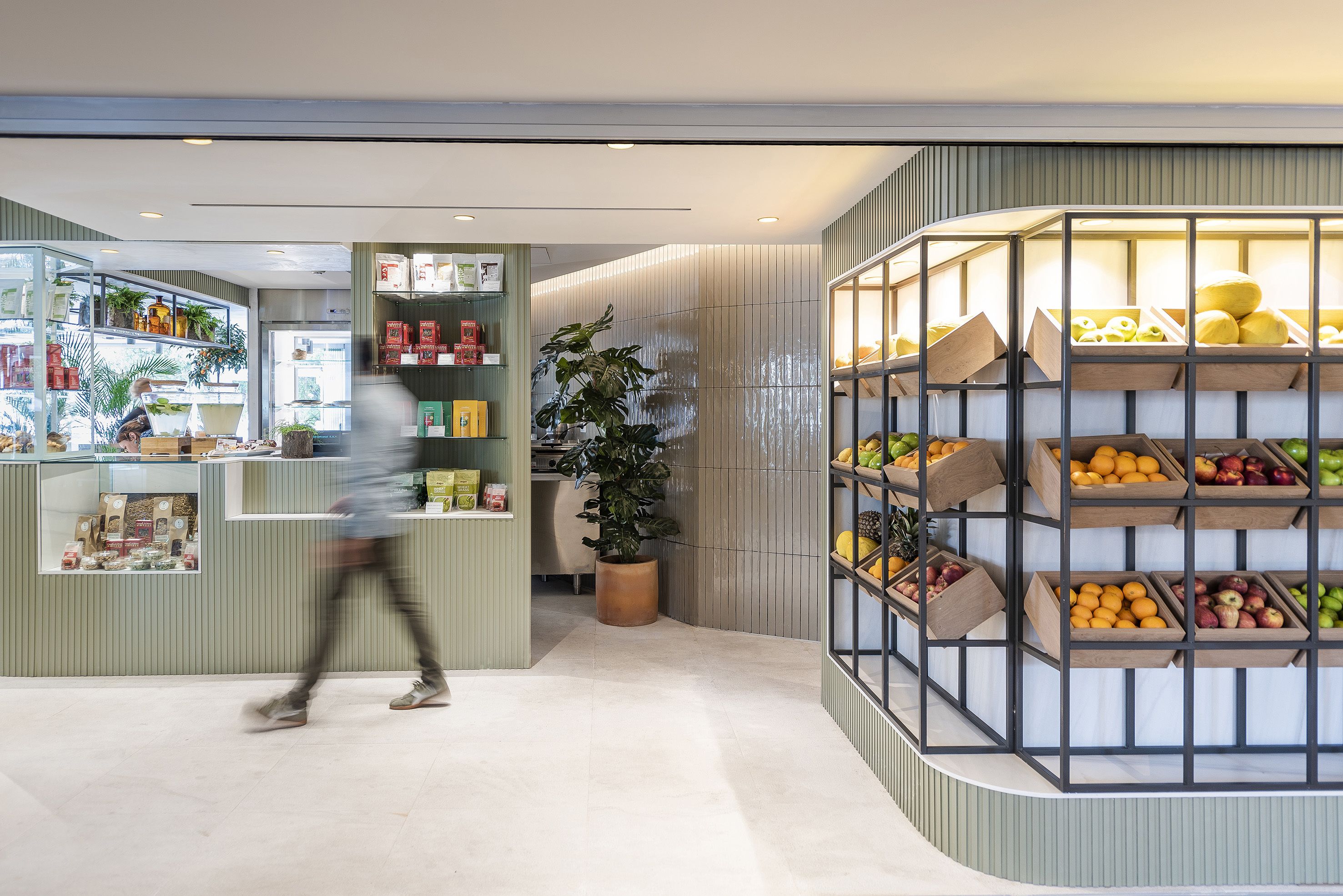 A modern retail space with a variety of products on shelves and in display cases, including fruits and packaged goods.