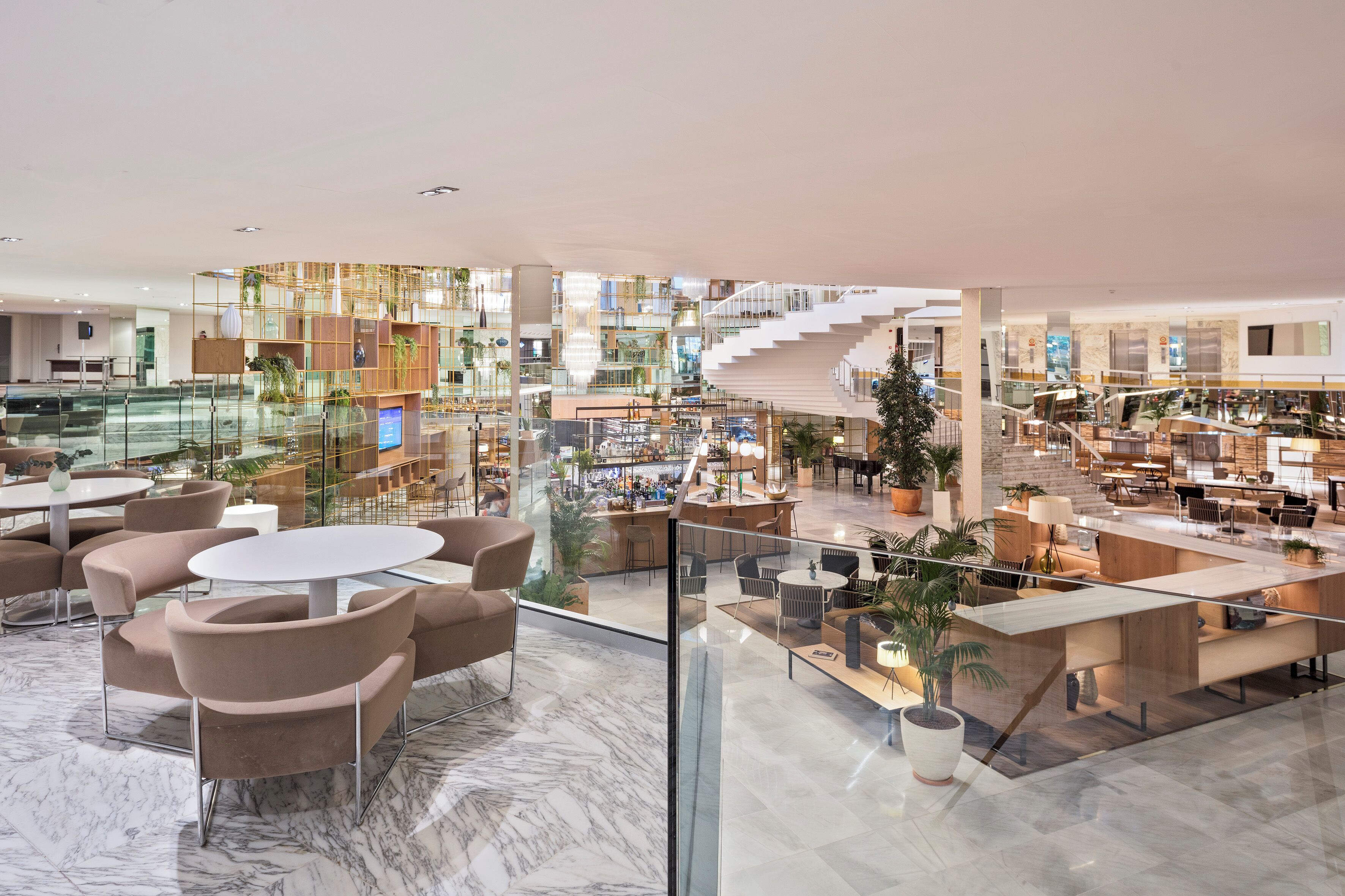 A spacious lobby with a glass railing, marble flooring, and multiple seating areas.