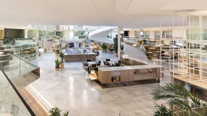 Un vestíbul espaiós amb paviment de marbre, zones d'estar, una recepció i una escala que condueix a les plantes superiors.