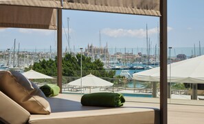 Habitación de hotel con vista a un puerto deportivo, mobiliario exterior y piscina.