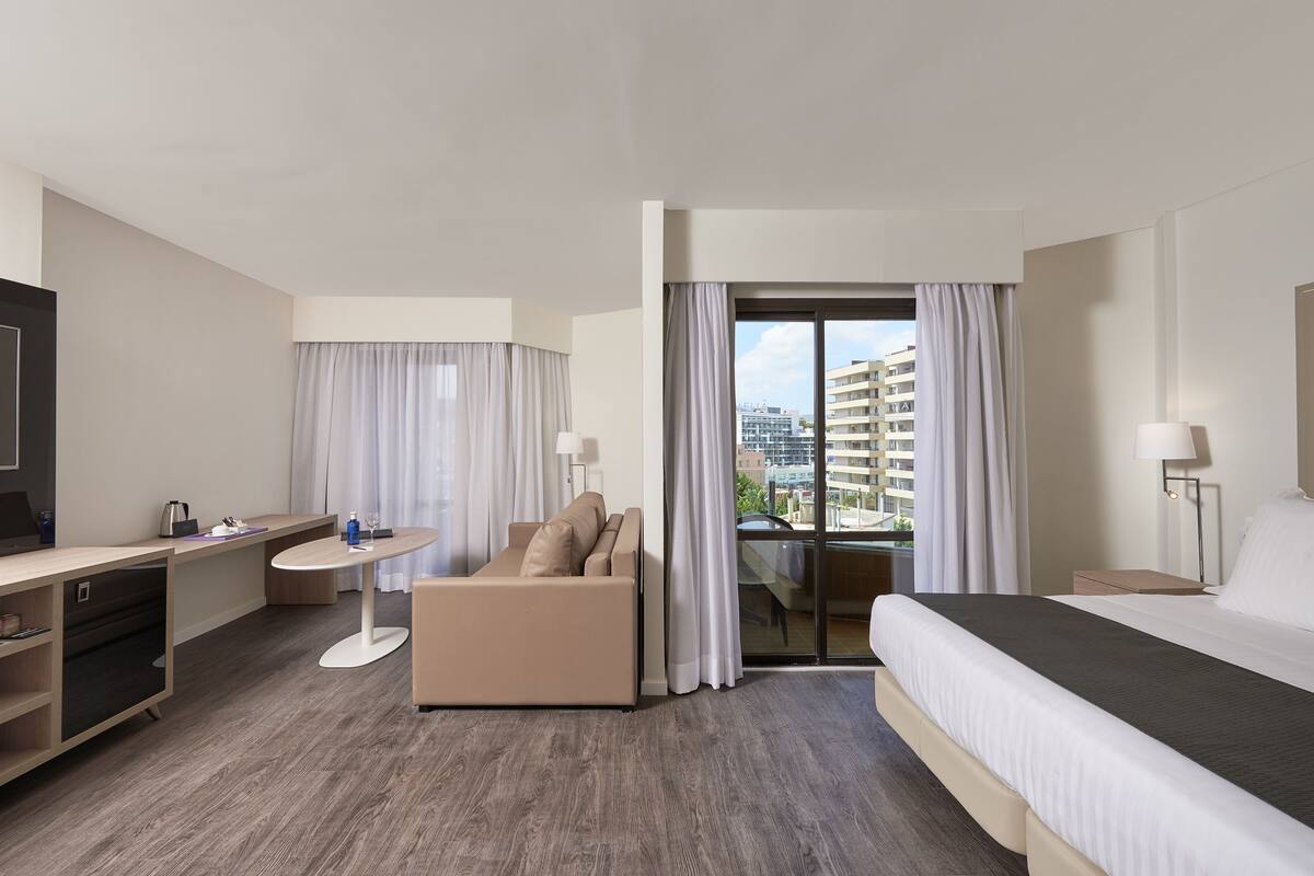Una habitación de hotel moderna con cama, sofá, escritorio y vistas a la ciudad.