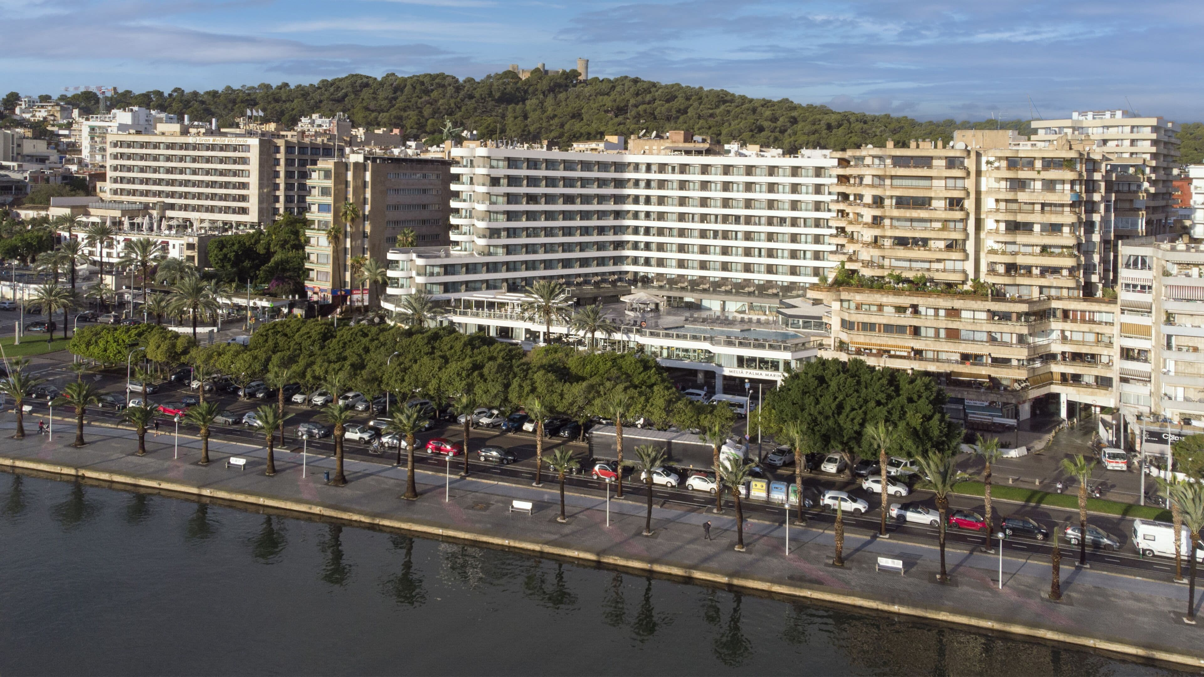 Un hotel de varios pisos con un diseño arquitectónico moderno, que cuenta con un patio central y vistas de la ciudad circundante.