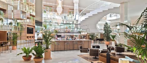 A spacious lobby with a bar area, seating arrangements, and a staircase.