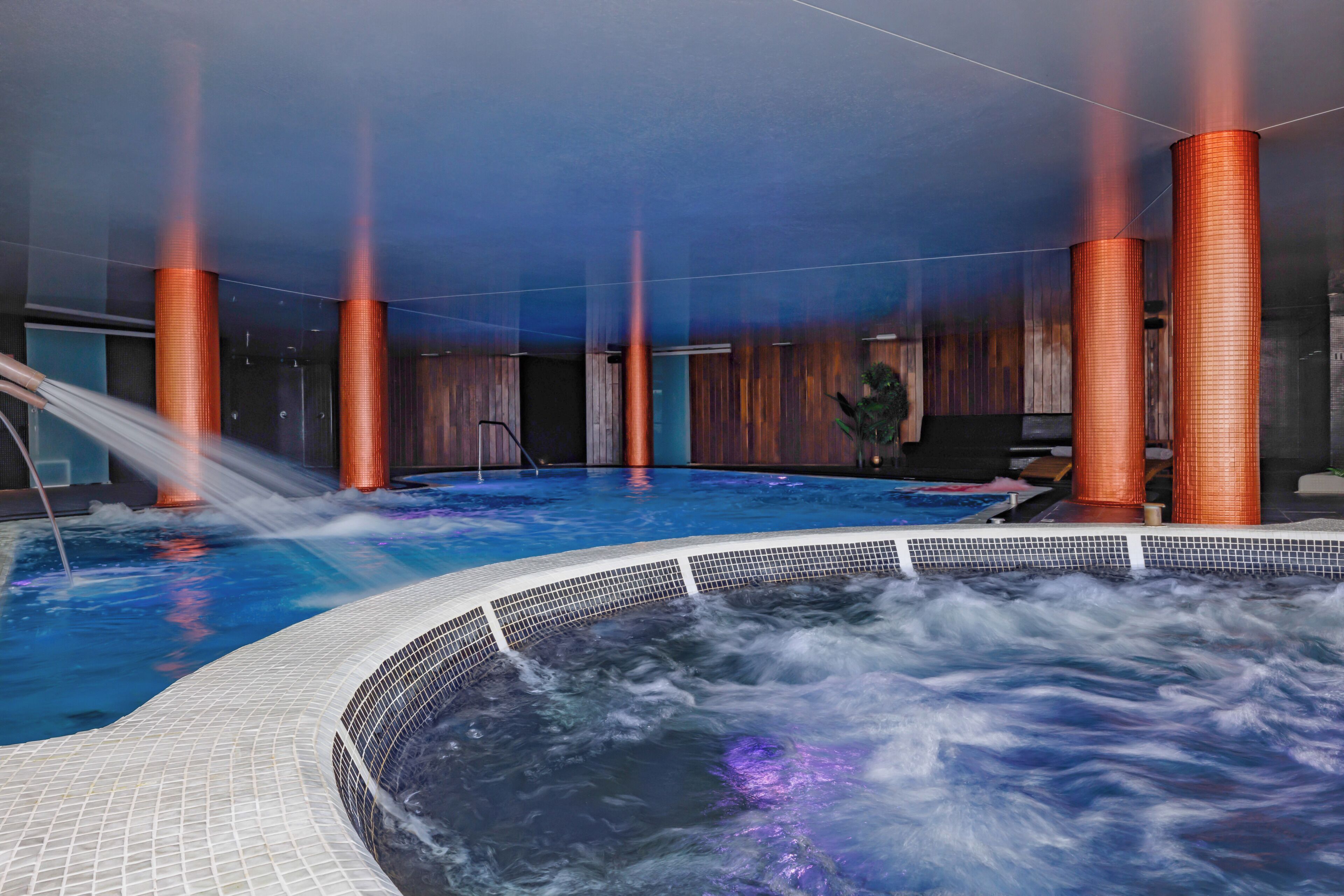Un jacuzzi con borde de azulejos y un elemento acuático.