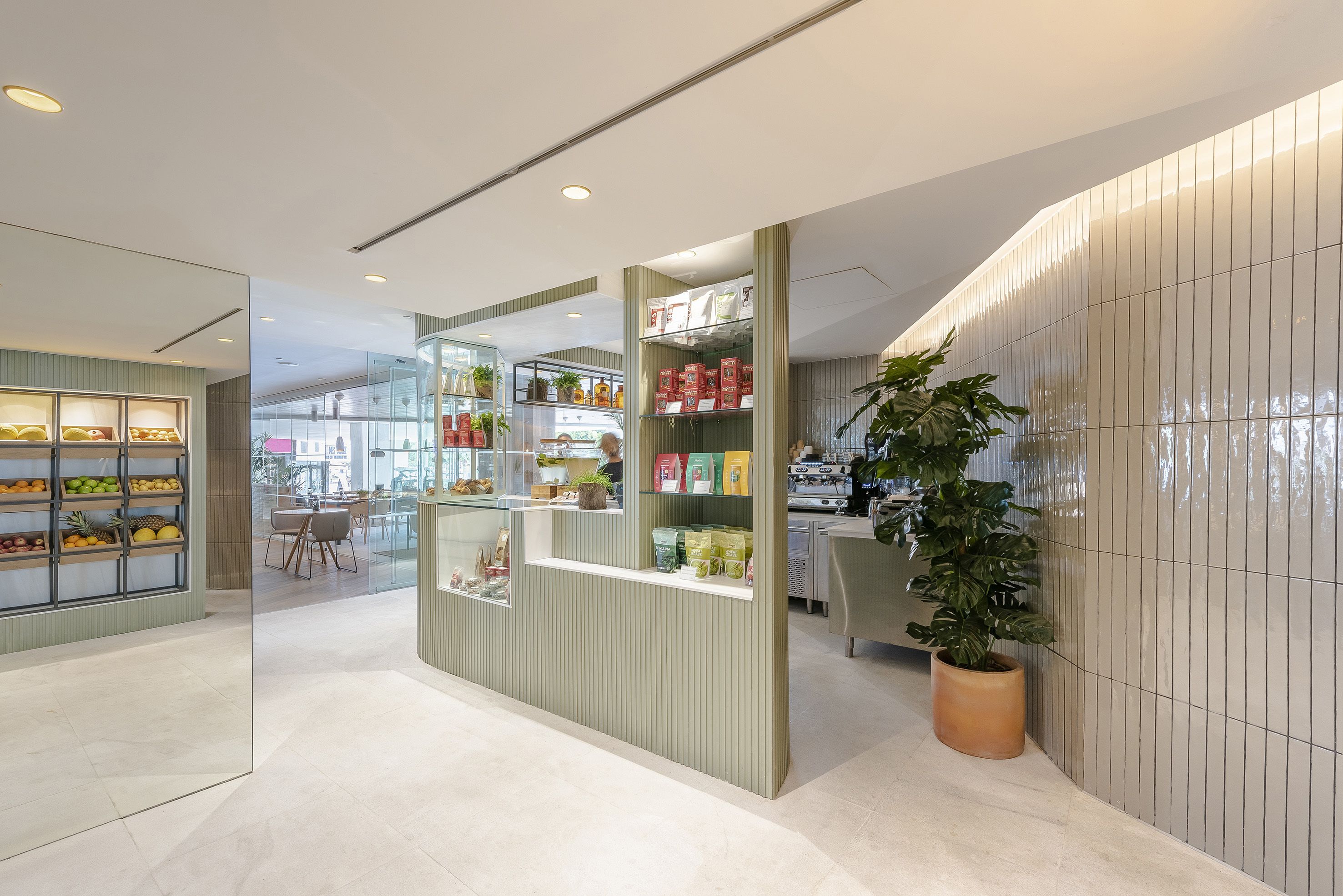Un interior moderno con una exhibición de frutas, un mostrador con productos envasados y una planta en maceta.
