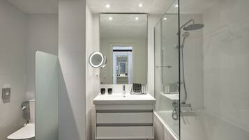 Une salle de bain moderne avec une douche à parois de verre, un lavabo blanc avec un miroir et des toilettes.