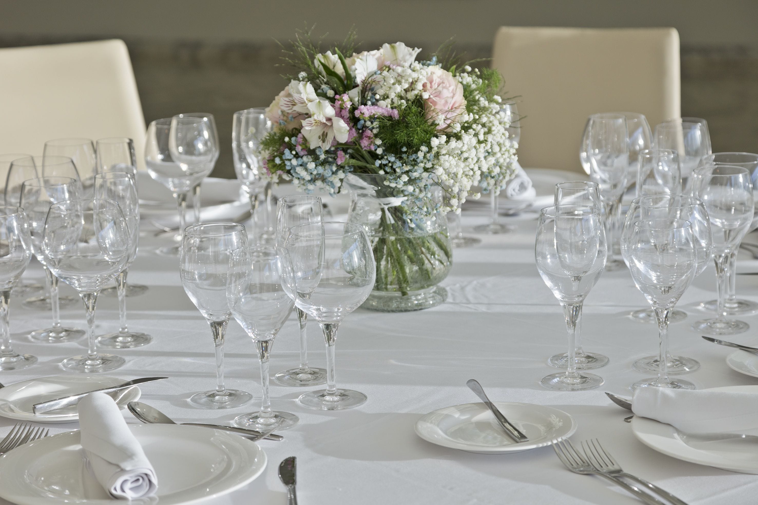 A table set for a formal event with multiple wine glasses, plates, and cutlery.