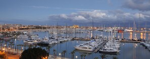 A marina filled with various boats and yachts, surrounded by a cityscape with buildings and palm trees. - Melia Palma Marina (Palma de Mallorca)