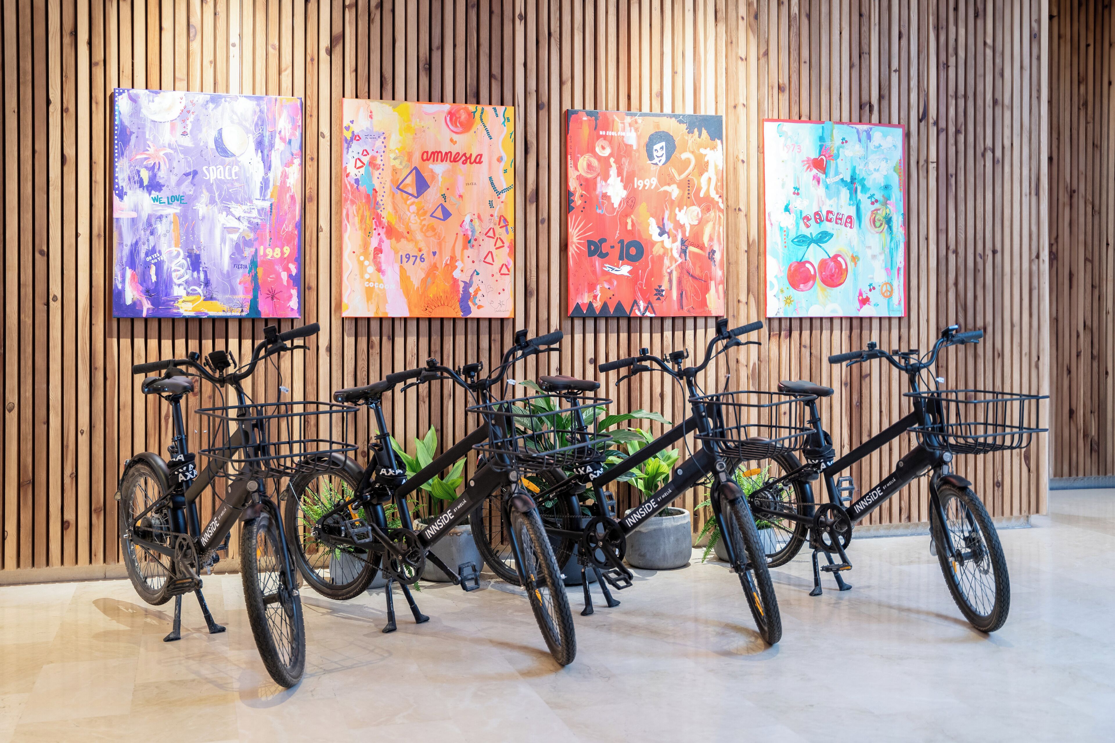 A row of bicycles parked against a wooden wall with colorful artwork.